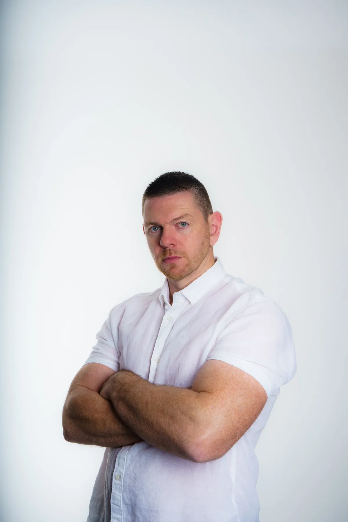 Homme en chemise blanche bras croisés sur fond blanc studio